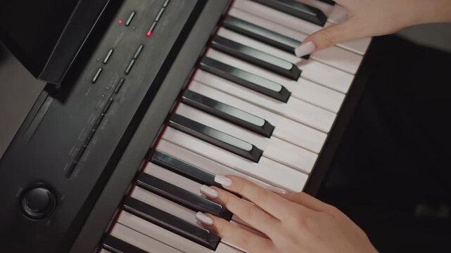 Closeup hands on keyboard practicing. Young student pianist rehearses scales and arpeggios on a black electronic keyboard, concentrated fingerwork and precise technique under soft studio lighting,