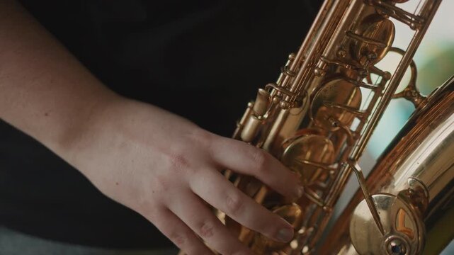 Close up fingers on saxophone keys during solo rehearsal, performer warming up in rehearsal room, brass shine, focused articulation and improv practice, casual black shirt, neck strap visible,
