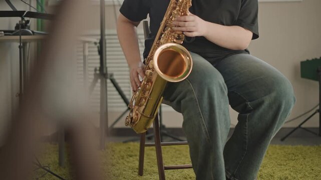 White saxophonist close leg and bell shot during teaching session, focus on foot tapping and stool posture, amp and mic in background, friendly educational atmosphere, morning light