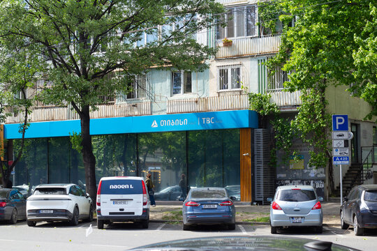 Tbilisi, Georgia - May 20, 2026: Street photo. Cars on parking near bank house with TBC logo on blue wall. Gel, lari bill. Concept of salary, credit, cash money, ATM, loan, debt, pay tax, plastic card