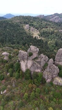 Dramatic Aerial push in shot of two rock climbers resting on the summit of a steep rocky crag surrounded by a vast pine forest in Mineral del Chico, Hidalgo, Mexico, 4K 60fs vertical drone shot