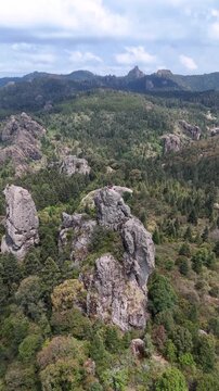 Astonishing Aerial push in shot of rock climbers standing on a steep rocky crag surrounded by a vast pine forest in Mineral del Chico, Hidalgo, Mexico, 4K 60fs vertical panoramic drone shot