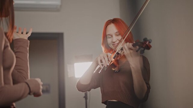 Female musician perfecting bowing techniques. Artist refining posture and playing strategies with mentor. Female violinist and coach collaborating during rehearsal with focus and guidance