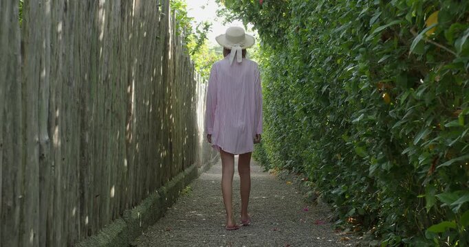 Woman in vacation walking down a narrow path in nature.