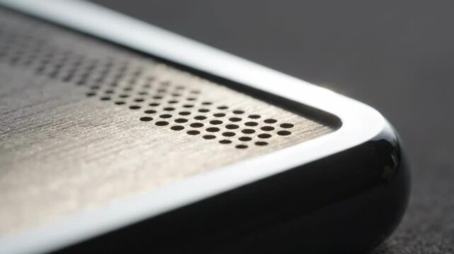 Close up of metallic speaker grill on modern device