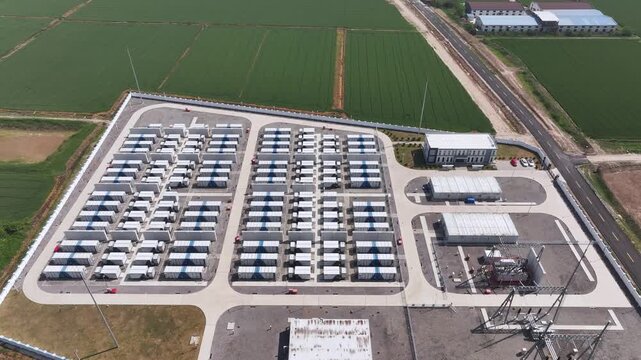 Aerial view of energy storage station equipment beside farmland with battery modules and power infrastructure
