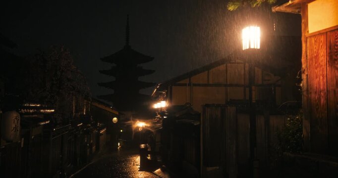 Steady cam movement through ancient Japanese village at night with lamps and heavy rain fall