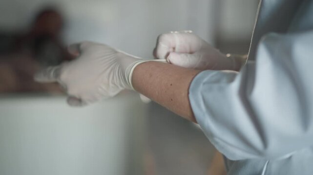 Medical professional carefully manages infection control measures at bedside. Nurse in protective attire attentively performs patient care with strict infection prevention protocols