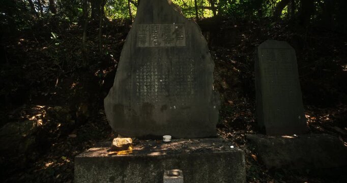 Slow steady movement towards shadowy stone with Japanese engravings in forest