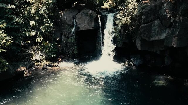 Drone footage establishing shot facing a cinematic waterfall hidden in the tropical jungle