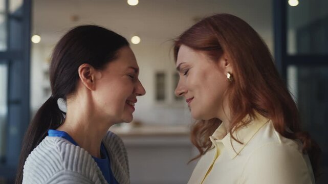 Two middle-aged women friends reconciling after quarrel and leaning foreheads