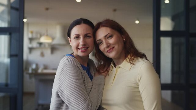 Portrait of two middle-aged women friends hugging and smiling warmly