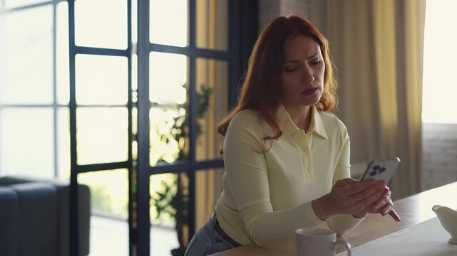 Upset middle-aged woman reading message on smartphone, stressed by bad news