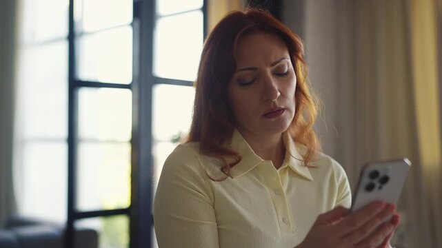 Sad woman in her 40s typing on smartphone after receiving bad news message