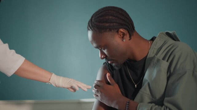 Patient gets vaccination. Man receives immunization comfort. Male individual receives reassuring vaccination process. Male recipient is comforted and reassured throughout immunization procedure