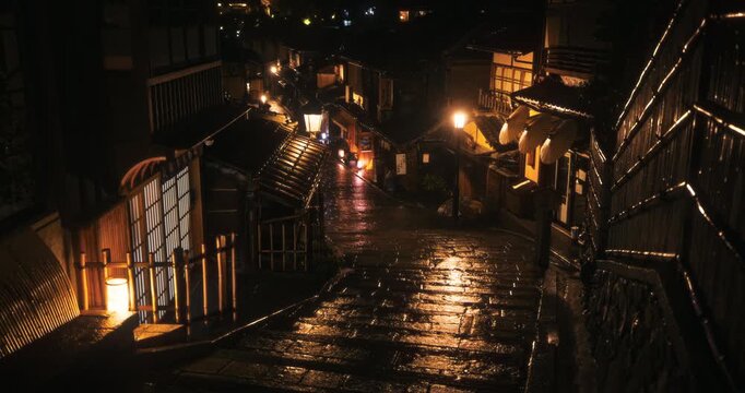 Soaked cobblestone steps through ancient Japanese village at night with lamp light - high shot