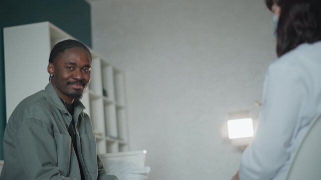 Patient smiles happily. Patient appears at ease sharing health concerns with clinician. Relaxed individual displaying joyful expression while discussing treatment options with healthcare provider
