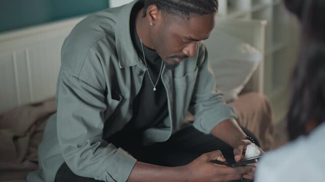 Man carefully examines medicine packaging while reading labels carefully. Male individual scrutinizes prescription box with focused attention under bedside lighting to ensure proper dosage