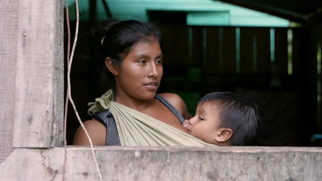 An indigenous mother from the Cab&eacute;car community in Costa Rica breastfeeding her baby in a baby carrier 