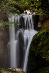Obraz premium Triberger Wasserfälle im Schwarzwald mit sonnenbeschienenem, herabstürzendem Wasser und moosbewachsenen Felsen 