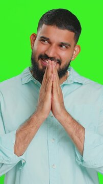 Sneaky cunning Indian young man with tricky face gesticulating and scheming evil plan, thinking over devious villain idea, cheats, jokes, pranks. Arabian guy isolated on green chroma key background