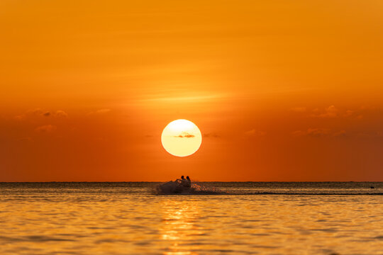 Jet ski silhouette crossing tropical sunset sea