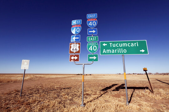 Historic Route 66 and interstate 40 highway road sign pointing towards Tucumcari and Amarillo against clear blue sky.