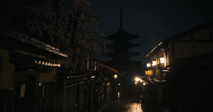Steady cam movement through rainy, ancient Japanese town at night