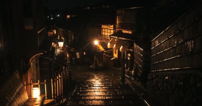 Glistening, wet, cobblestone road in old Japanese village at night - wide, high shot