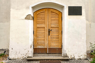 Fototapeta premium Old wooden church door with cracked historic facade in Czech village obec Vrbatky, Czech Republic - May 3, 2026