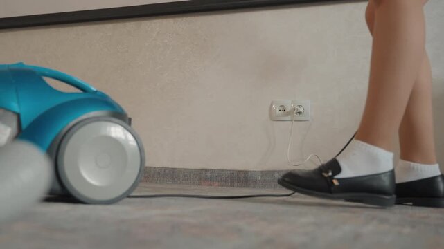 Cleaning process begins with power connection. Housekeeper connects device prior to cleaning session. Domestic helper is plugging in vacuum cleaner before starting household cleaning activities