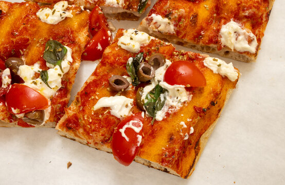 Colorful tray pizza or pinza in artisanal bakery in Rome, food of Italy, street food for lunch, with tomatoes, salami, basil, mozzarella