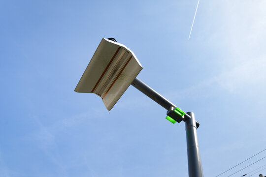Modern KVB e-bus charging mast with a green light against a blue sky with contrail. Green mobility and public transport infrastructure in Germany.