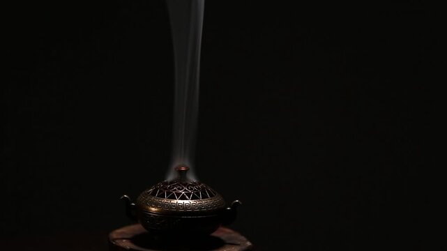 Blue texture smoke from incense aroma stick in vintage old design metal box motion rising above on copy space dark background. Meditation, yoga, wellness, aroma calm relaxation concept