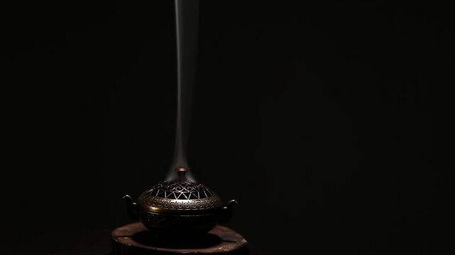 Blue texture smoke from incense aroma stick in vintage old design metal box motion rising above on copy space dark background. Meditation, yoga, wellness, aroma calm relaxation concept