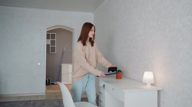 Woman organizing study. Young woman arranging study essentials. Female preparing neat home learning area. Young woman arranges notebooks and lighting in minimalist home study area for grammar lessons