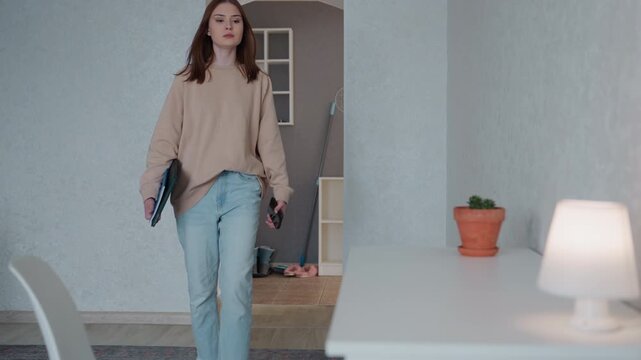 Modern woman prepares learning space. Individual organizes digital and paper study tools. Woman arranges stationery and digital devices in sleek modern interior for online tutoring sessions