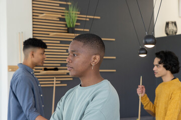 Obraz premium Diverse male friends standing around pool table under pendant lights holding cues and watching