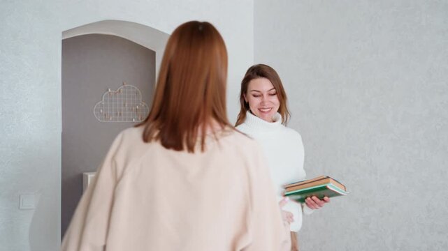Tutor arrives at doorway with books, friendly entrance scene in bright modern apartment, tutor offers materials and a smile to student, brief handshake and exchange of notebooks, welcoming atmosphere