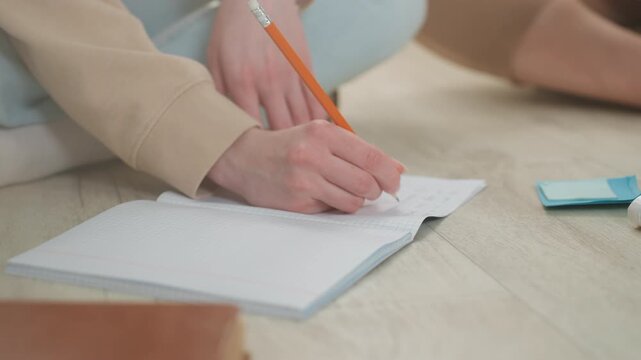 Female coach taking notes during intensive grammar drill, closeup hand movement, spiral notebook and pencil in frame, materials and eraser nearby, coach mentoring adult student, concentrated energy,