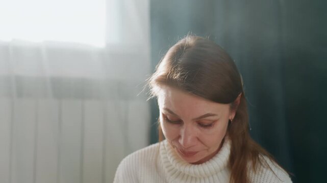 Caucasian woman tutor at home reviewing grammar notes in soft window light, white sweater, focused expression, marking errors and preparing lesson plan, calm mentoring vibe for one on one study