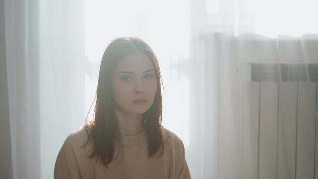 Caucasian woman tutor in sunlit room sitting near window, soft backlight, thoughtful expression, coaching grammar, corrective feedback, home study, cozy sweater, radiator and sheer curtains