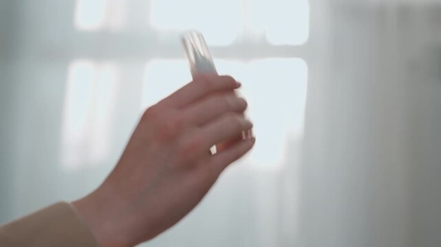 Caucasian tutor holding correction fluid bottle, soft morning light through window, closeup of hand demonstrating grammar correction technique for home tutoring session fingers grip small transparent