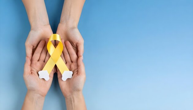 Hands grasping a yellow ribbon and a bone, representing the fight against bone cancer during Sarcoma Awareness Month