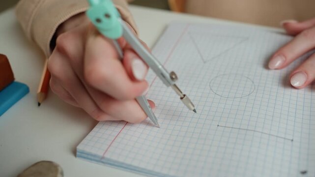 Closeup white hands using compass, graph paper grid, precise circle drawing, math tutor demonstration, engineering layout, steady measurement, pencil point on paper, study session