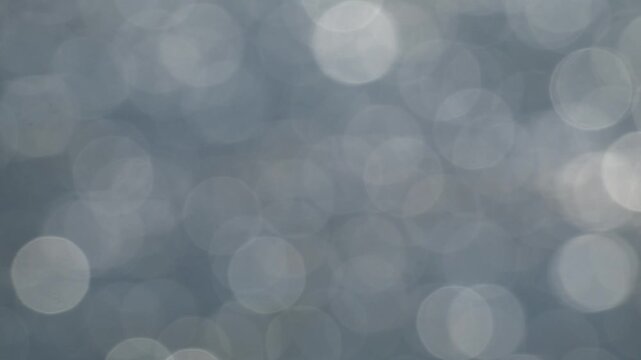 Waves with bokeh on water surface on a windy, sunny day, glittering and reflecting light. Nature background.