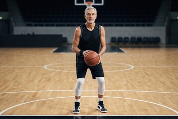 Fototapeta premium An athletic older man poised with a basketball on a court, showcasing strength, determination, and the spirit of the game.