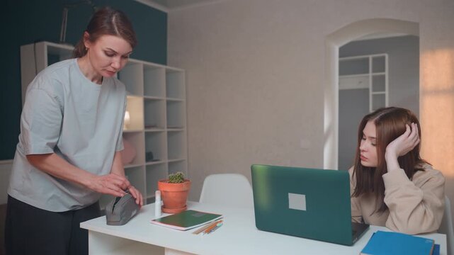 Home design lesson white coach demonstrating color swatch samples on table beside laptop, student listens thoughtfully, potted plant and bookshelf backdrop, handson material guidance, soft evening