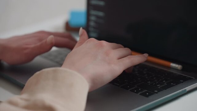 Focused student typing beside pencil closeup hands typing on laptop near pencil resting on keyboard editing draft proofreading punctuation and syntax at home desk quiet natural light study routine