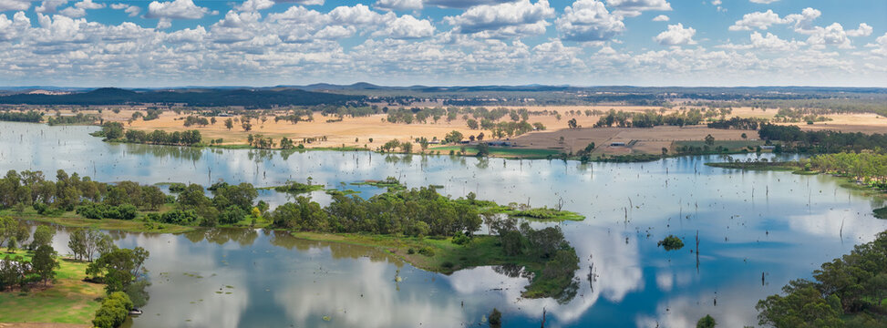 Aerial panorama view clouds reflected on an inland river alongside dry farmland